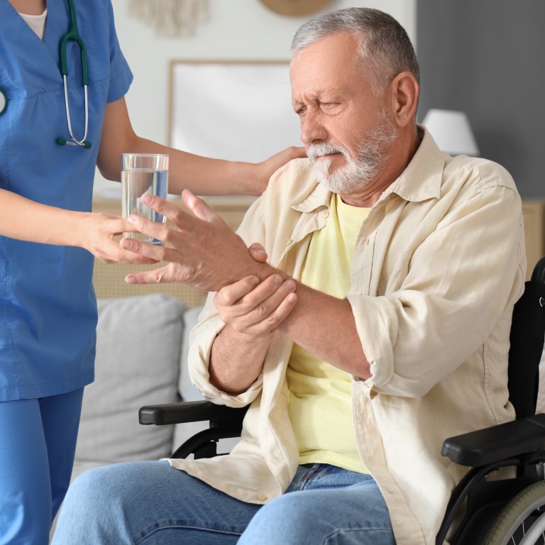 Pflegekraft hilft Senior im Rollstuhl mit einem Glas Wasser Pflegekraft reicht einem Senior im Rollstuhl ein Glas Wasser