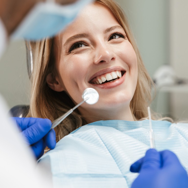 Zahnarzt bei der Untersuchung einer Patientin mit zahnärztlichen Instrumenten Zahnarzt untersucht Patientin mit blauen Handschuhen und zahnärztlichen Instrumenten