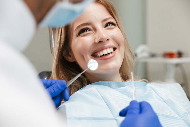 Zahnarzt bei der Untersuchung einer Patientin mit zahnärztlichen Instrumenten Zahnarzt untersucht Patientin mit blauen Handschuhen und zahnärztlichen Instrumenten