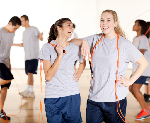 Fröhliche Jugendliche nutzen Sprungseile im Sportunterricht.