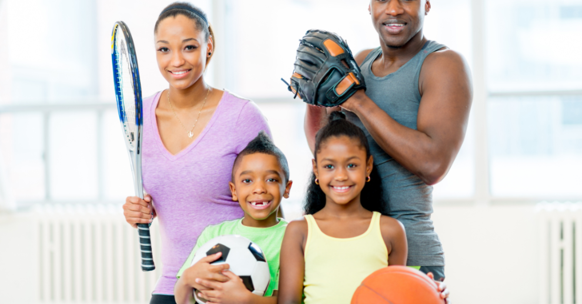 Familie bei sportlichen Aktivitäten mit verschiedenen Sportarten Familie hält Sportausrüstung für Tennis, Fußball, Basketball und Baseball.