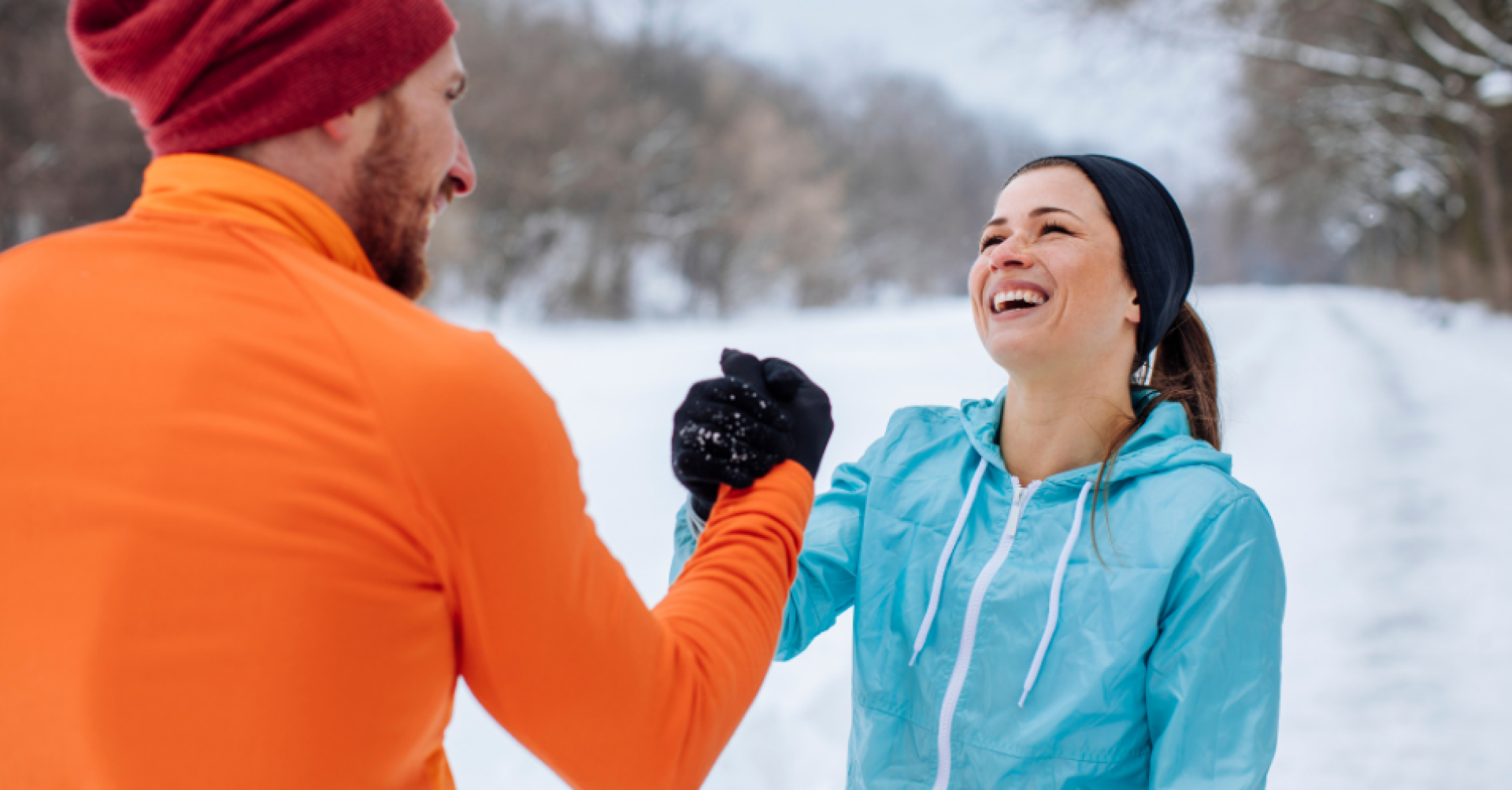 Sportliche Begrüßung im Winter: Zwei Personen im Schnee geben sich die Hand Zwei Menschen in Sportkleidung begrüßen sich im verschneiten Park mit Handschlag