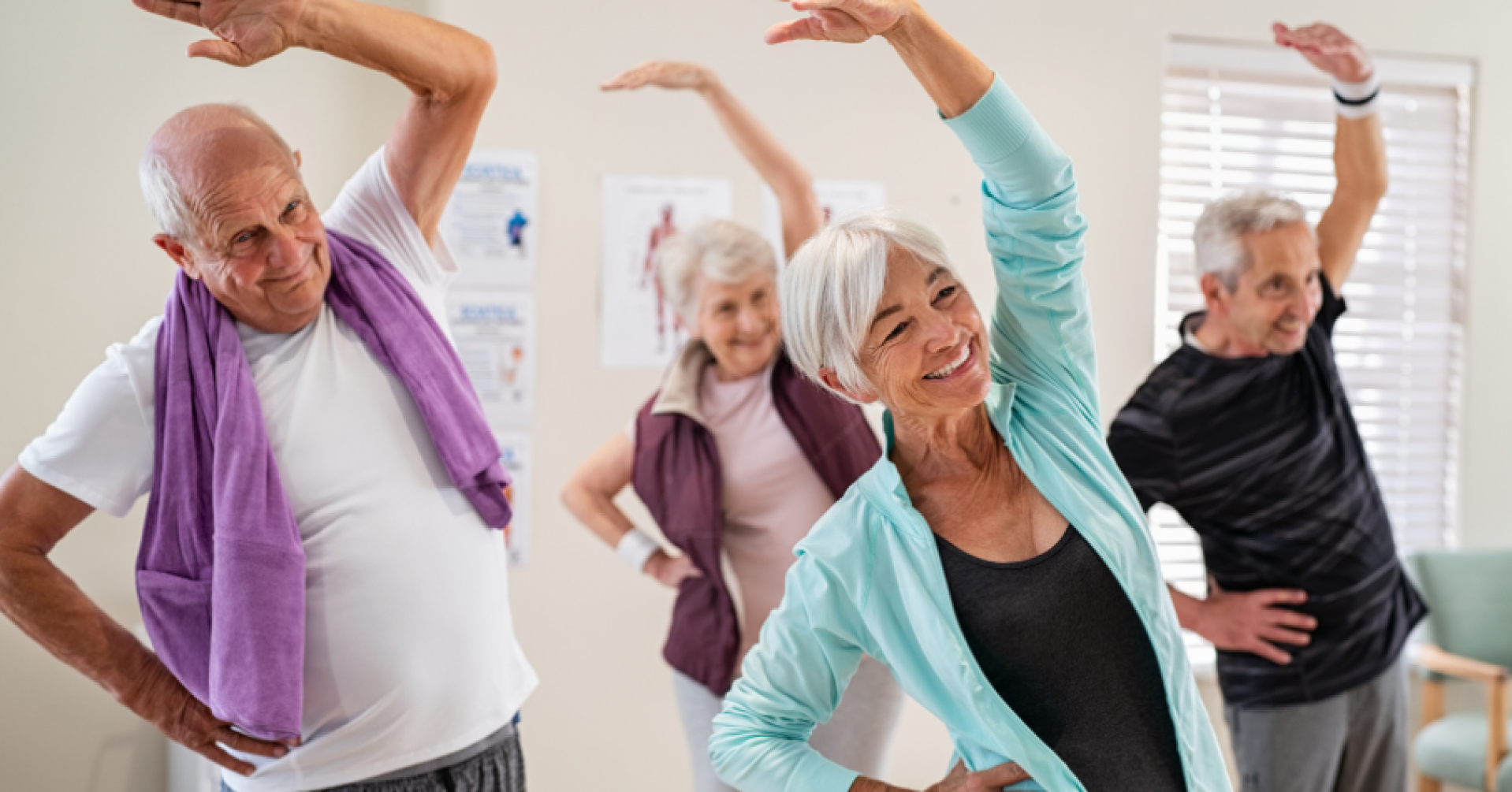 Senioren machen gemeinsam Gymnastikübungen in einem Fitnessraum