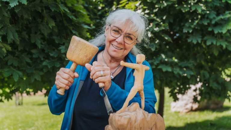 Holzschnitzkunst im Freien – alea alternativ s 21 Frau beim Holzschnitzen einer Figur im Freien, alea alternativ s 21