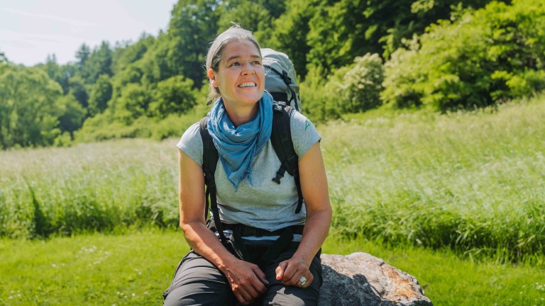 Frau mit Rucksack und Halstuch beim Wandern in der Natur, alea alternativ S 26
