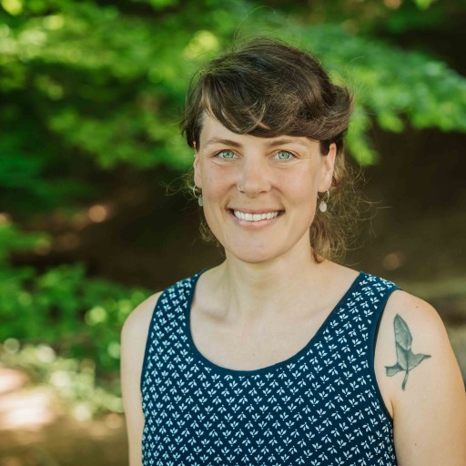 Alea Portrait im Sommer mit Tattoo am Arm und blauem Kleid im Grünen