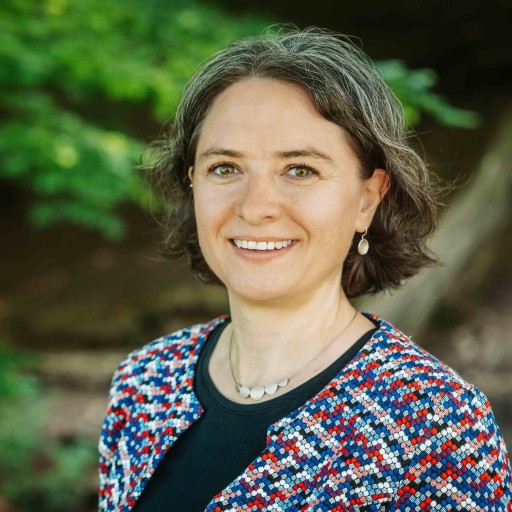 Alea Portrait – Frau mit bunter Jacke und Halskette im Grünen Alea Portrait einer Frau mit kurzem braunen Haar und bunter Jacke im Grünen