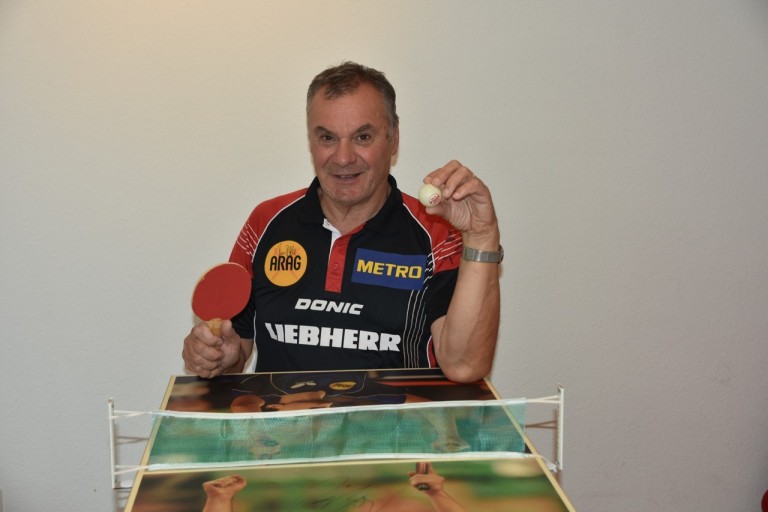 Norbert Müller beim Tischtennis mit Schläger und Ball, Sponsoren ARAG, METRO, DONIC und LIEBHERR auf dem Trikot