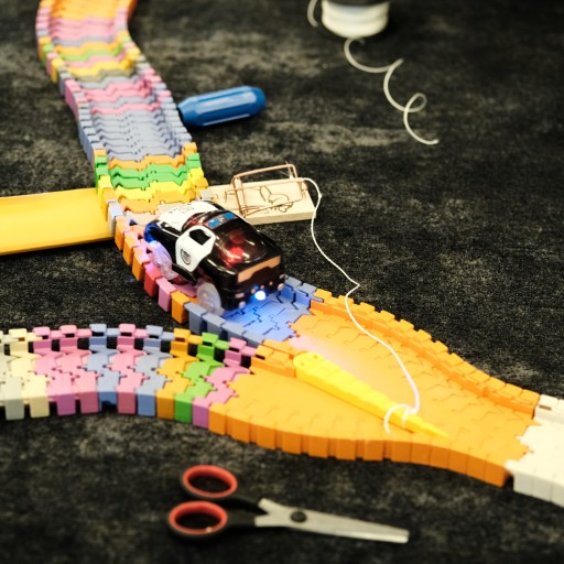 Spielzeug-Polizeiauto auf bunter Plastik-Rennbahn mit Schere und Faden auf Teppichboden