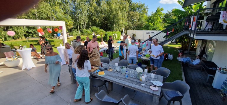 Sommerfest im Garten mit Gästen, gedecktem Tisch und entspannter Atmosphäre