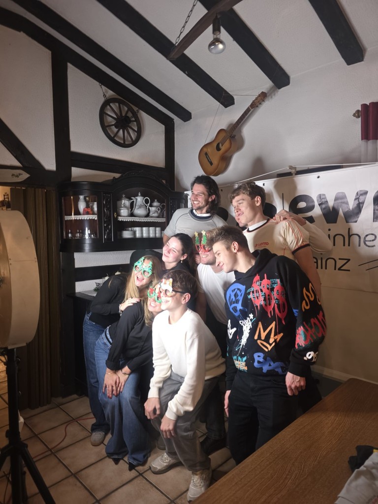 Gruppenfoto bei einer Feier in einem rustikalen Raum mit Dekoration und Banner im Hintergrund