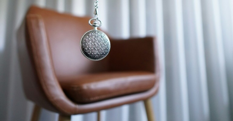 Hypnose – klassische Szene mit Taschenuhr im Therapieraum Hypnose mit Taschenuhr vor einem Sessel im Therapieraum