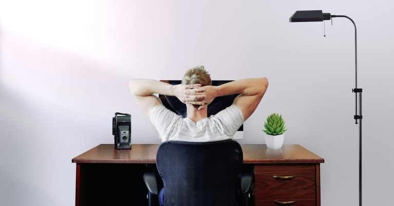 Mann mit verspanntem Nacken am Schreibtisch – typische Bürohaltung Mann mit verspanntem Nacken am Schreibtisch sitzt vor Computer und hält sich den Nacken