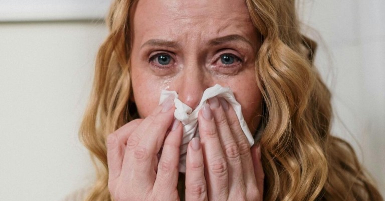 Symptome von Pollenallergie – typische Anzeichen und Beschwerden Symptome von Pollenallergie: Frau hält sich ein Taschentuch an die Nase