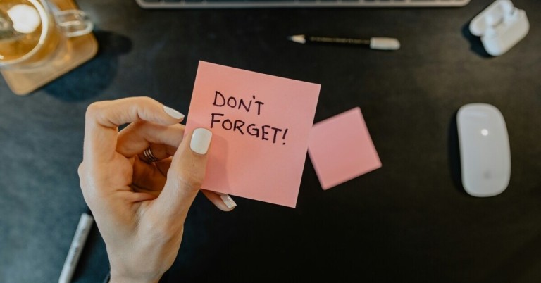 Hand hält pinken Notizzettel mit Aufschrift 'Don't forget!'