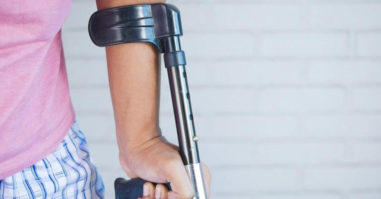 Unterarm mit Krücke vor hellem Hintergrund