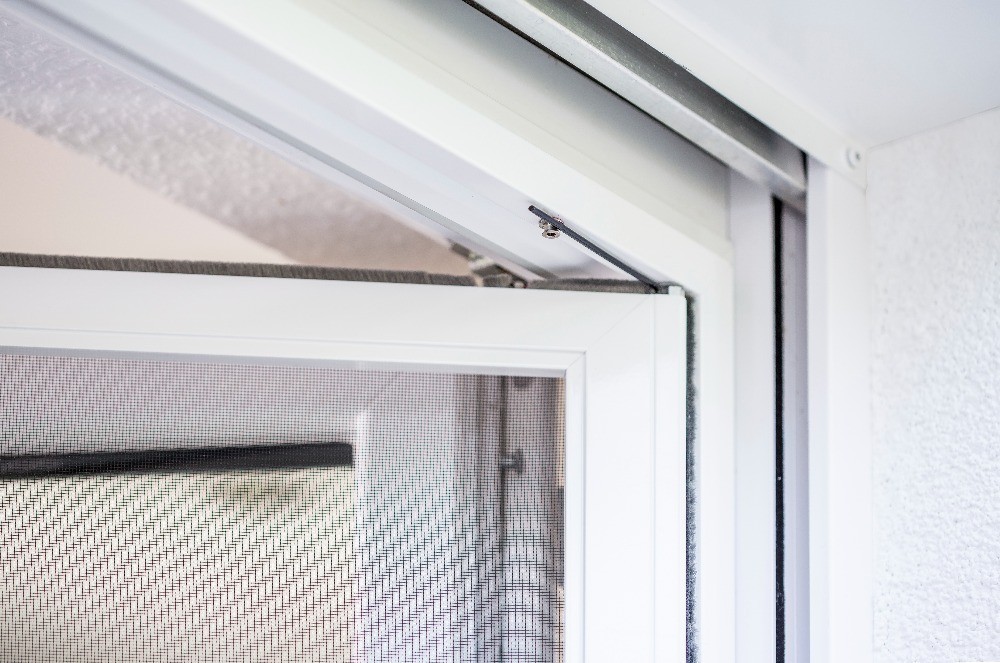 Nahaufnahme eines Fensterrahmens mit integriertem Insektenschutznetz