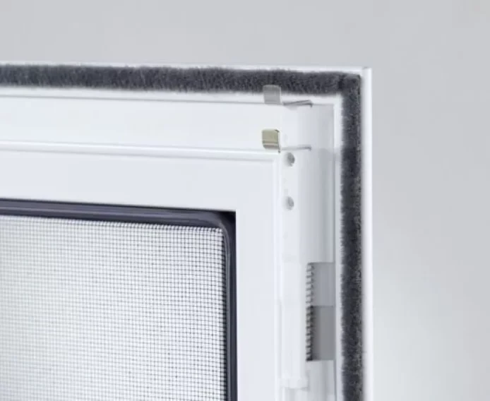 Nahaufnahme eines weißen Fensterfliegengitters mit Metallrahmen und Schutzbürste