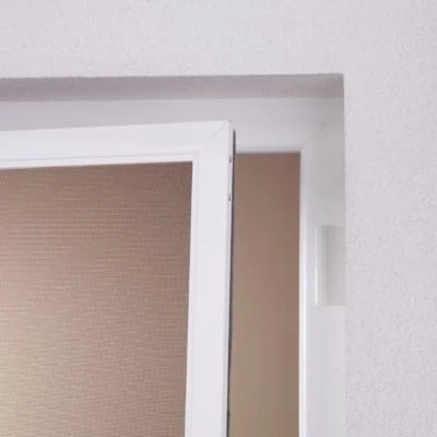 Detailaufnahme einer Drehtür mit Bürstendämpfung in einer weißen Wand.