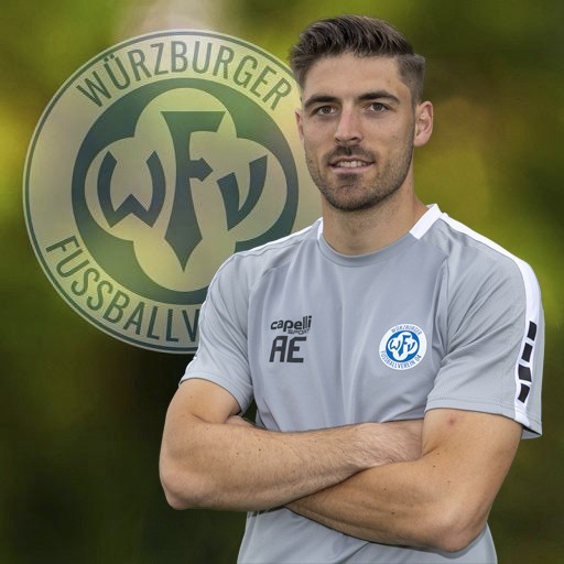 Fußballtrainer vor dem Logo des Würzburger FV Fußballtrainer in grauem Trikot vor Würzburger FV Logo